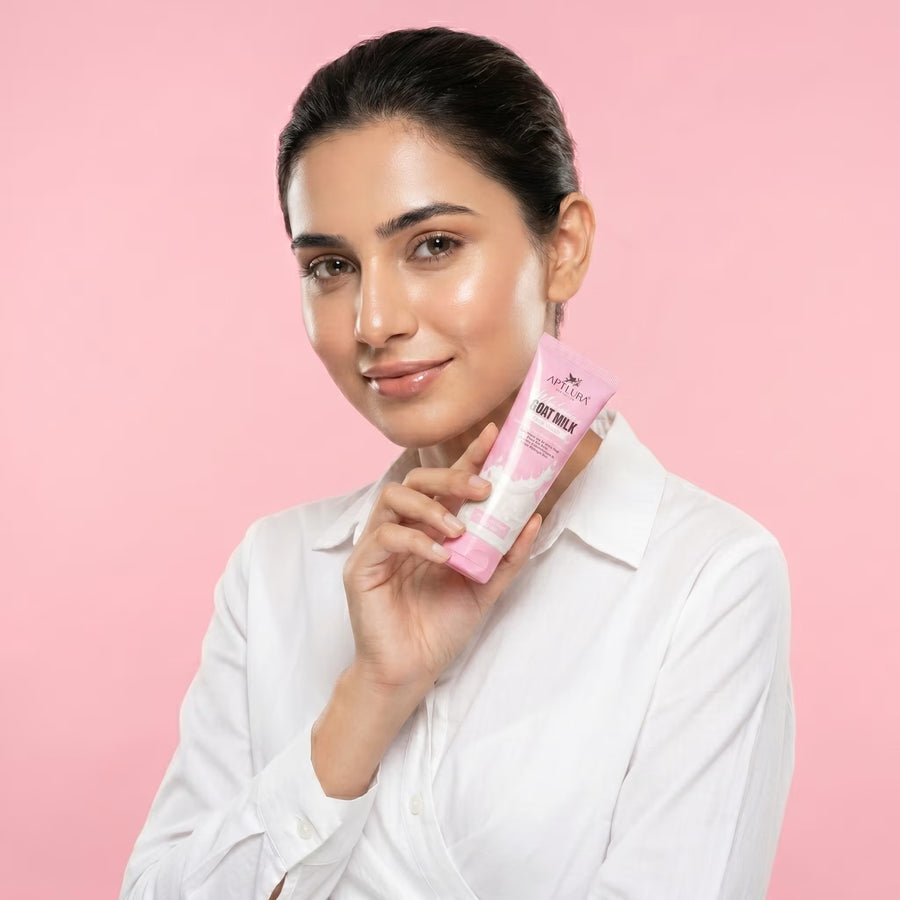 Woman holding a pink skincare product against a pink background