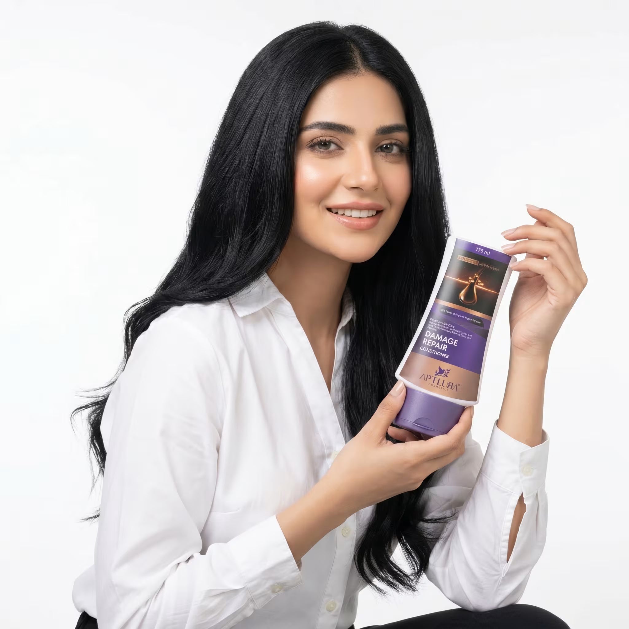 Woman holding a bottle of hair care product against a white background