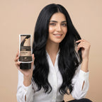 Woman with long black hair holding a bottle of hair conditioner against a beige background