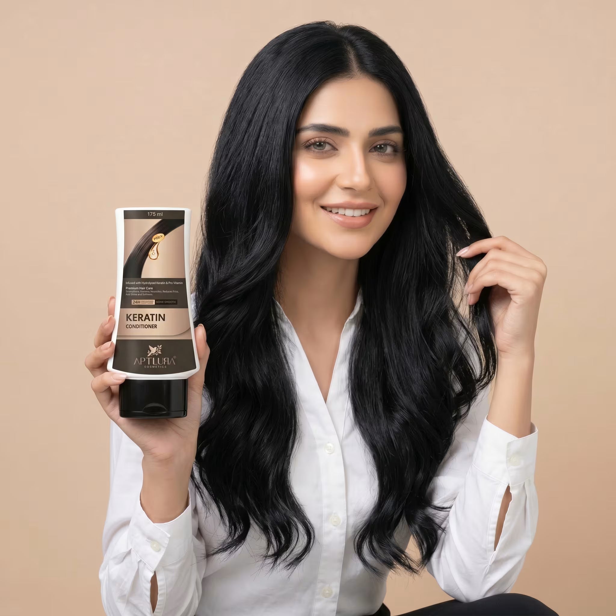 Woman with long black hair holding a bottle of hair conditioner against a beige background