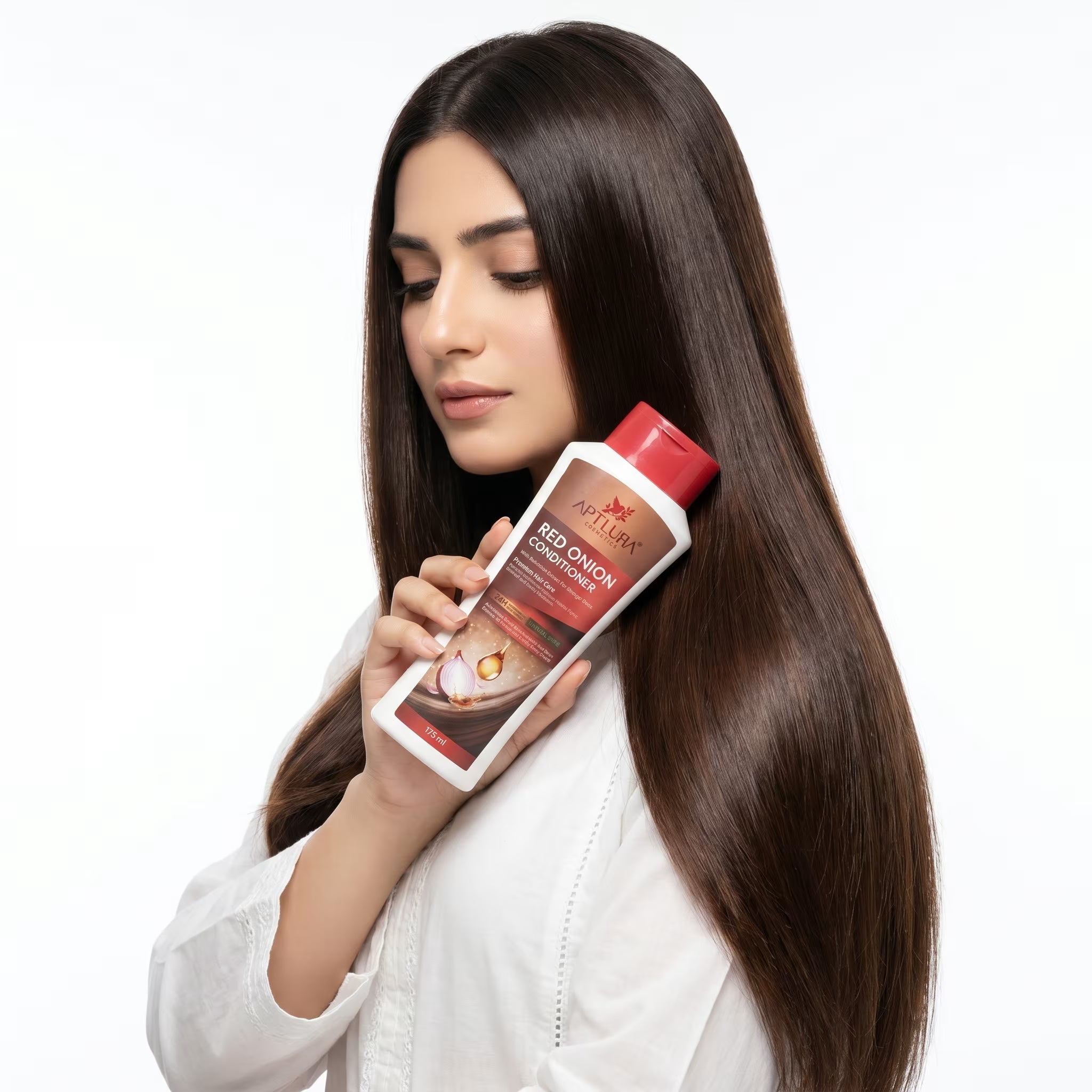 Woman with long brown hair holding a bottle of hair care product on a white background