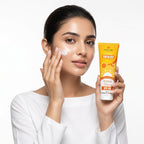 Woman applying sunscreen cream to her face with a tube of sunscreen in her other hand on a white background