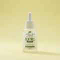 Tea tree serum bottle with dropper on a yellow background
