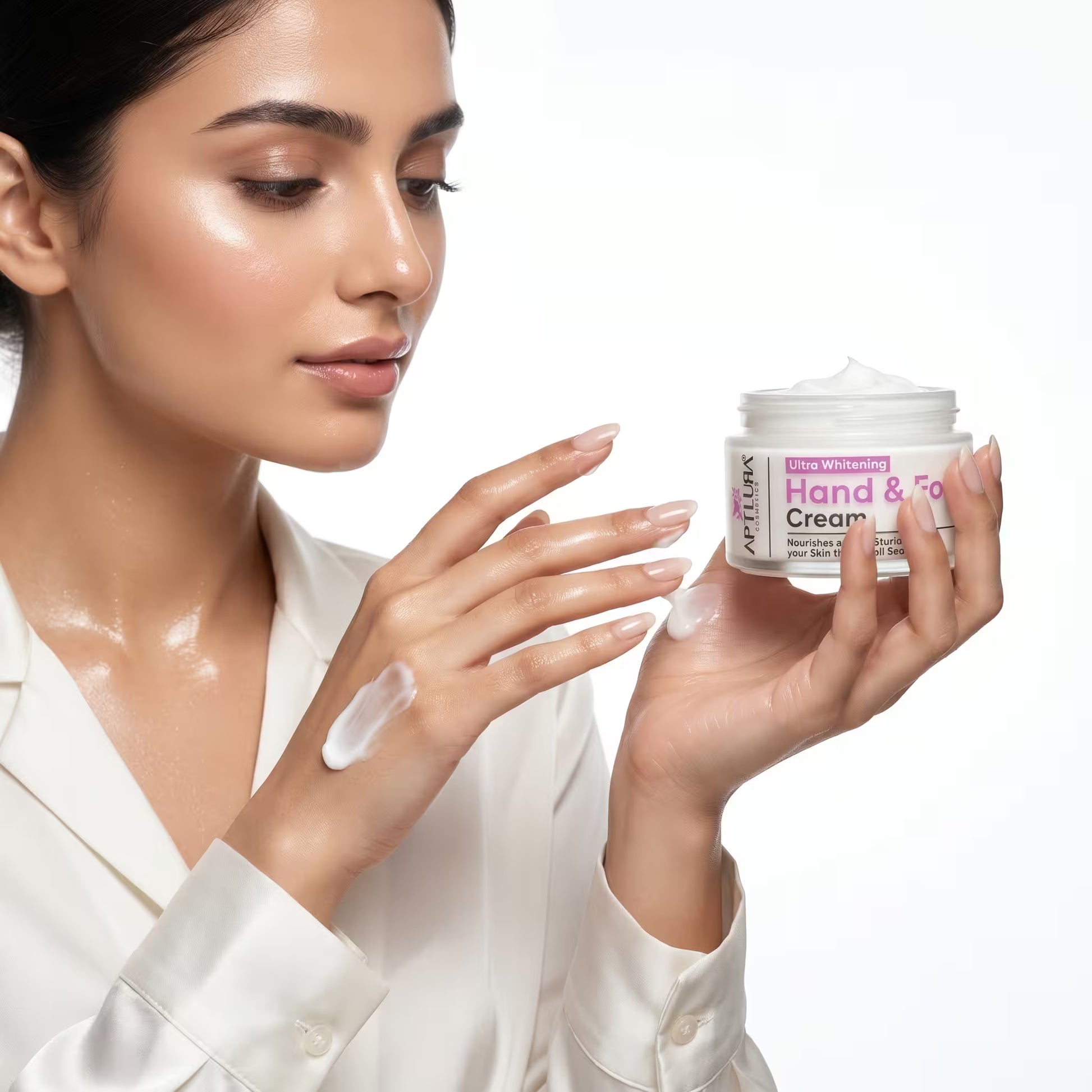 Woman applying hand cream to her hands with a jar of cream in front of her.