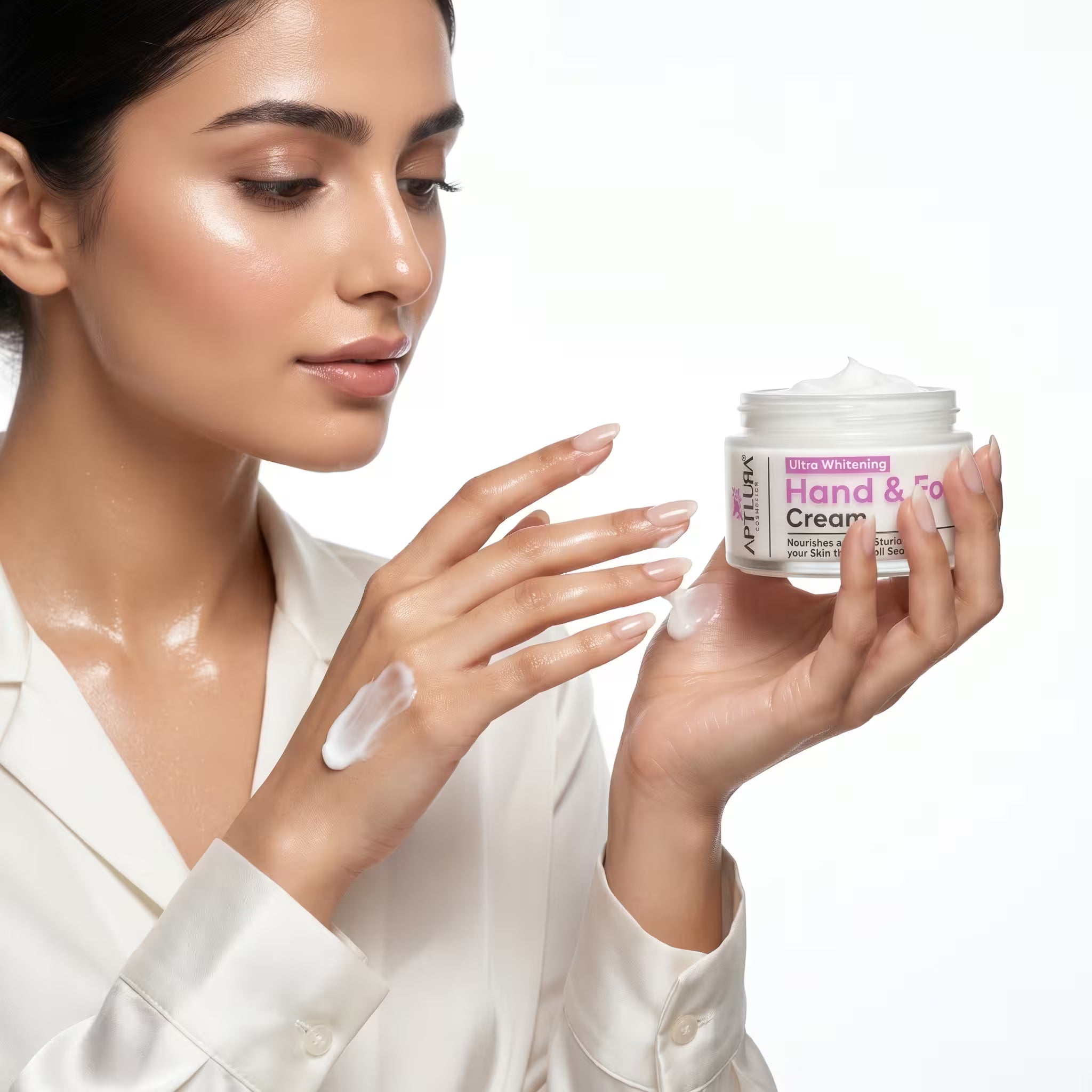 Woman applying hand cream to her hands with a jar of cream in front of her.