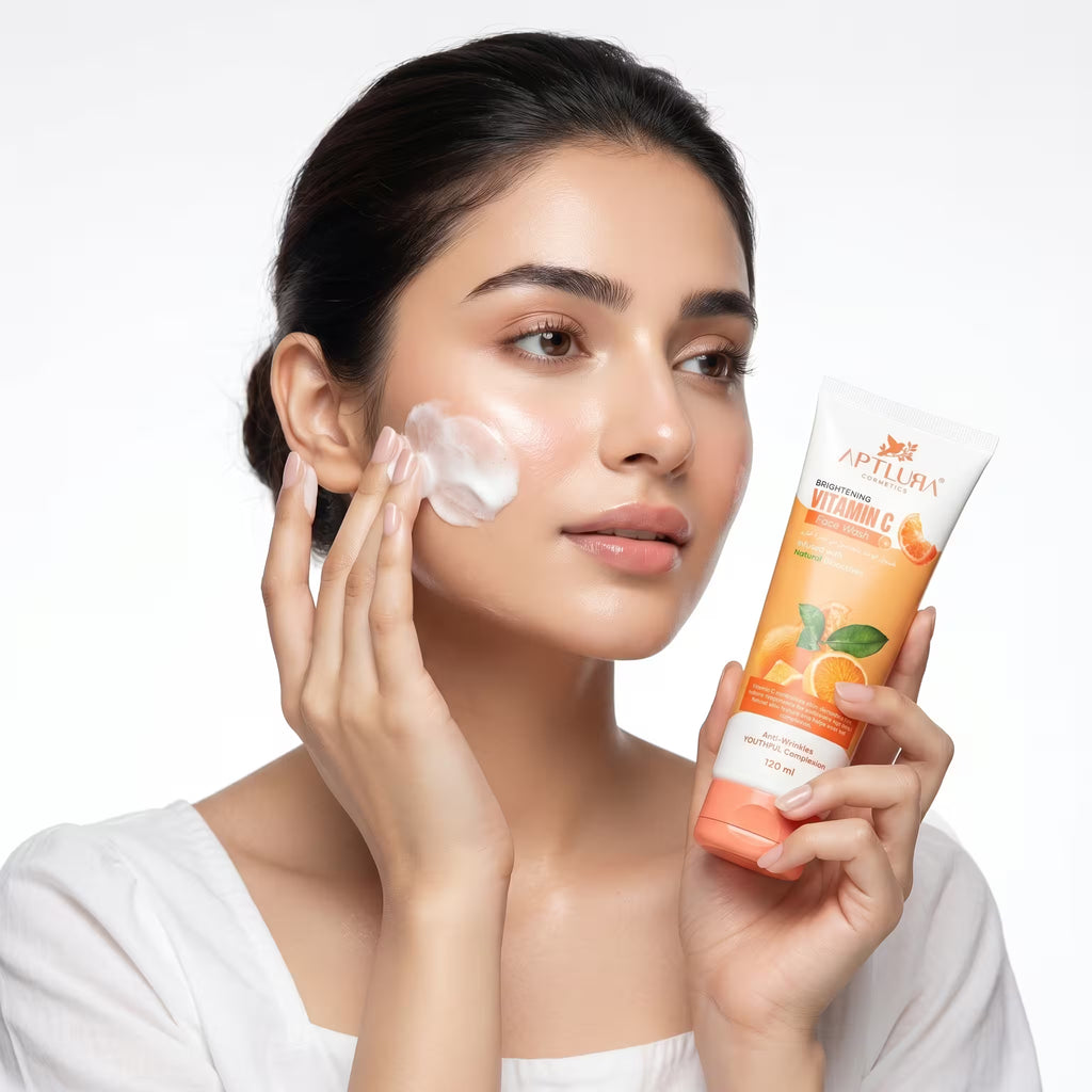 Woman applying facial cream with a tube of Aptlura Vitamin C product on a white background
