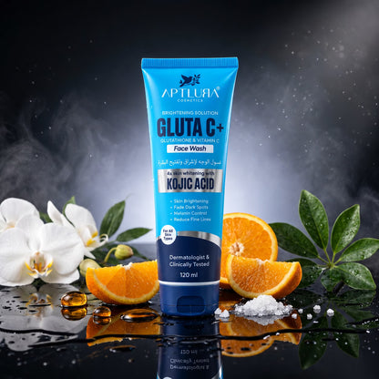 A tube of Aptlura Gluta C+ Face Wash stands upright on a glossy black surface with reflective water droplets. The tube is bright blue with white and dark blue text.