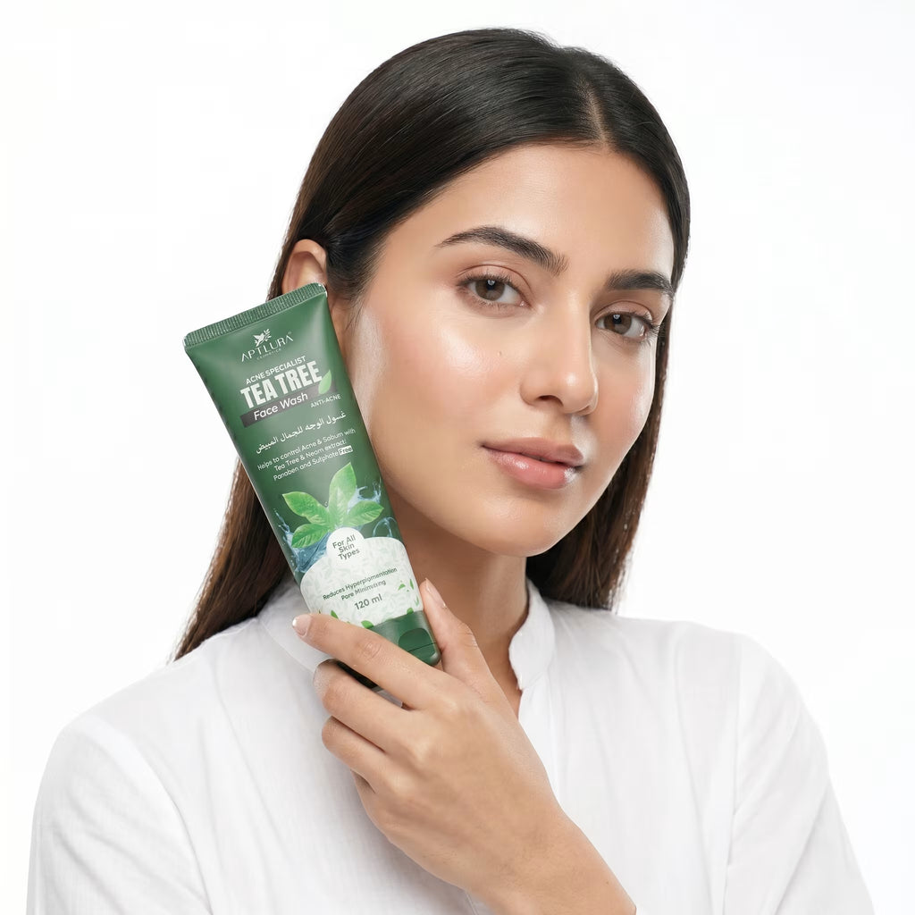 Woman holding a tube of tea tree face scrub with a white background