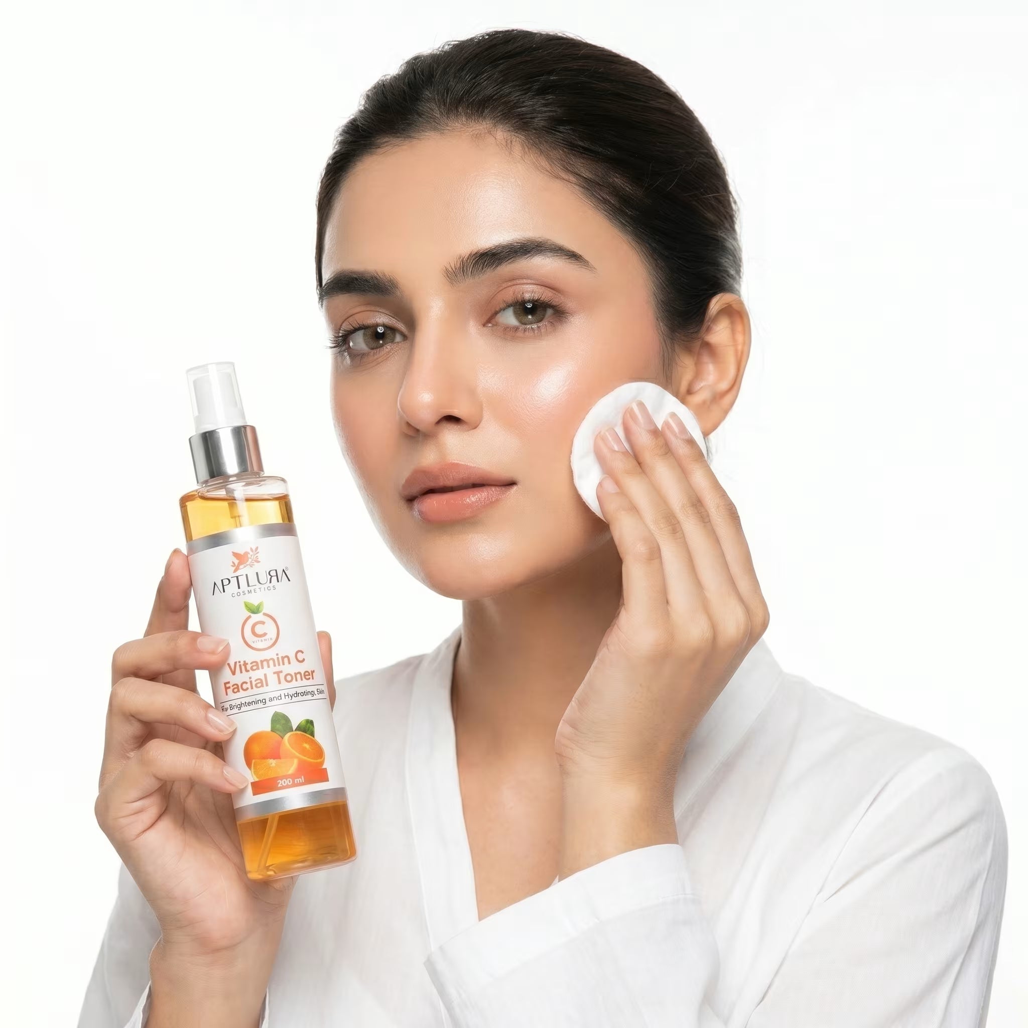 Woman applying facial toner with a cotton pad, holding a bottle of Aptlura skincare product.