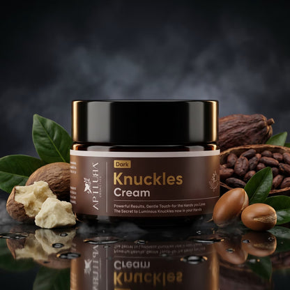 Jar of Dark Knuckles Cream surrounded by nuts and leaves on a reflective surface with a dark background