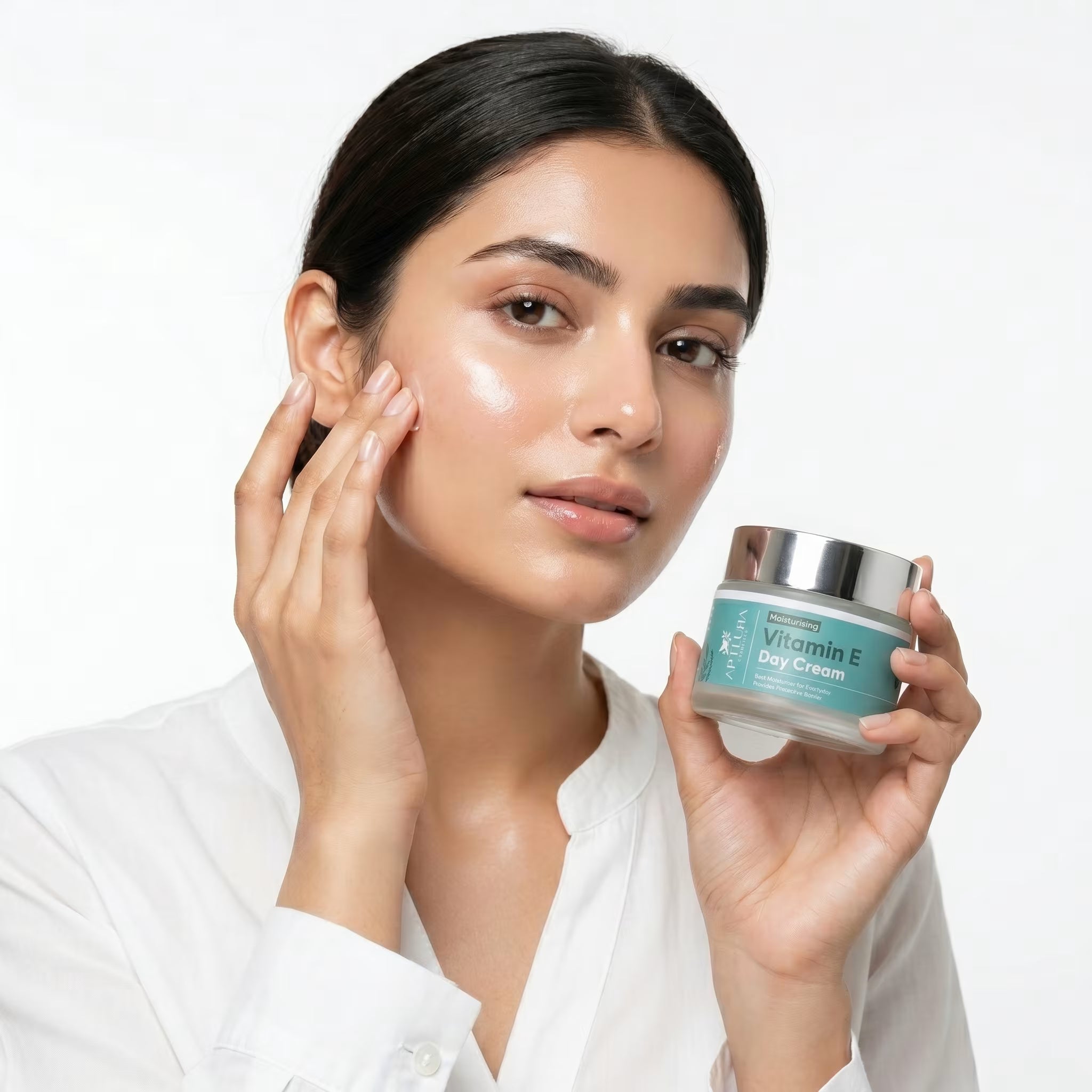 Woman applying cream to her face with a jar of Vitamin E day cream.